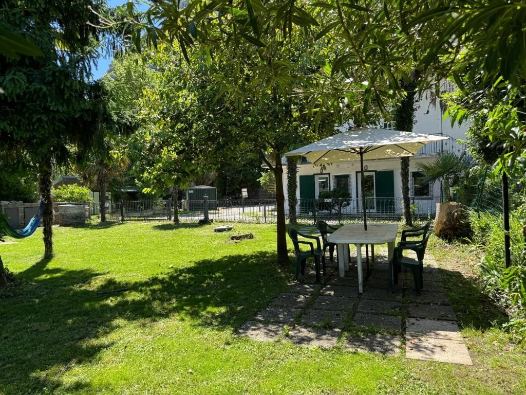 Un patio al aire libre con una mesa y sillas, rodeado de vegetaci ón y una cerca.