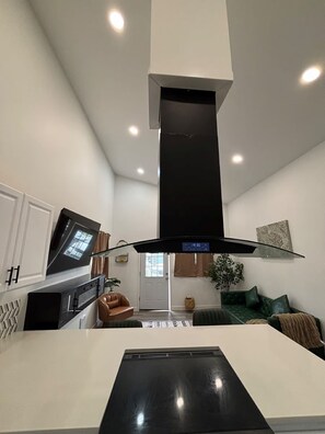 Una cocina moderna con una isla central, horno empotrado y campana extractora negra.
