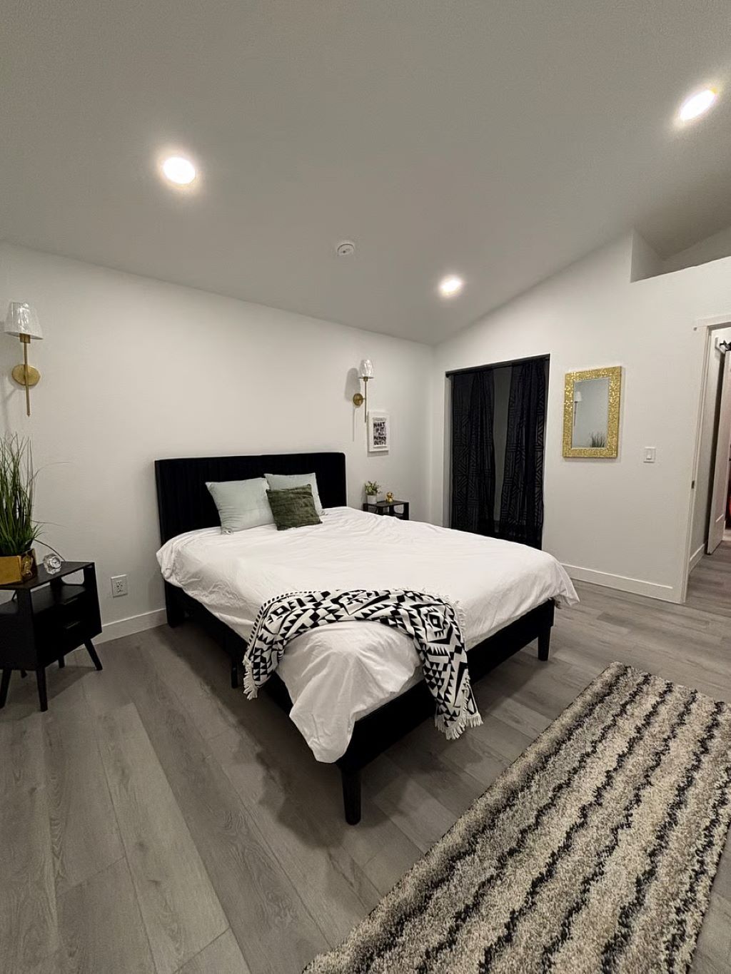 A modern bedroom with a large bed, bedside tables, a floor lamp, and a rug.