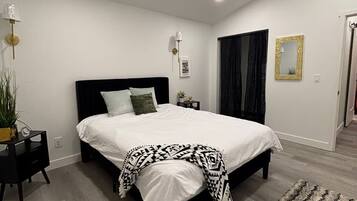 A modern bedroom with a large bed, bedside tables, a floor lamp, and a rug.