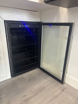 Een kleine, moderne keuken met een ingebouwde oven en een deur van geëtst glas.