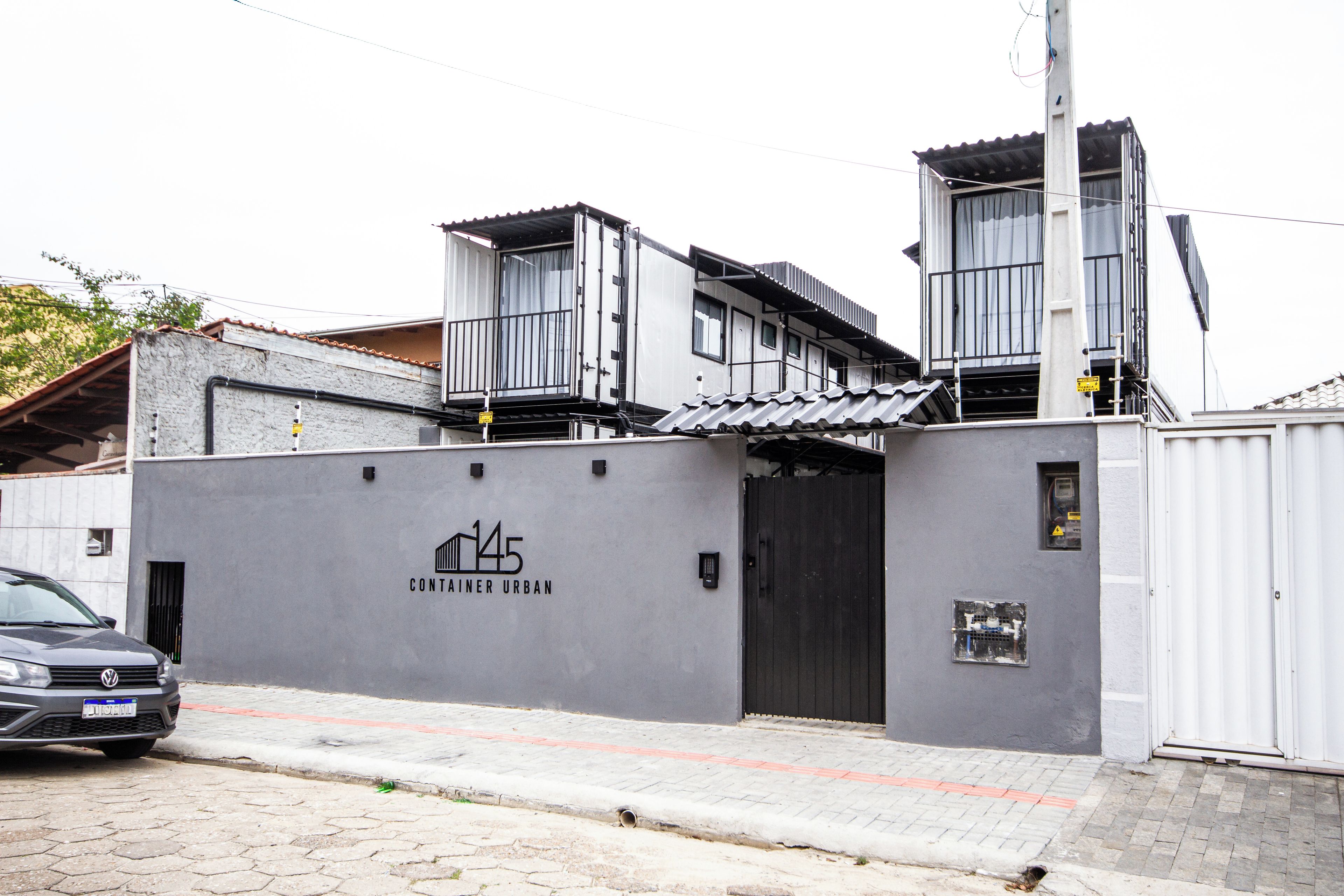 A modern building with a grey facade, a visible entrance, and a sign indicating 'CONTAINER URBAN'.