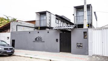 A modern building with a grey facade, a visible entrance, and a sign indicating 'CONTAINER URBAN'.