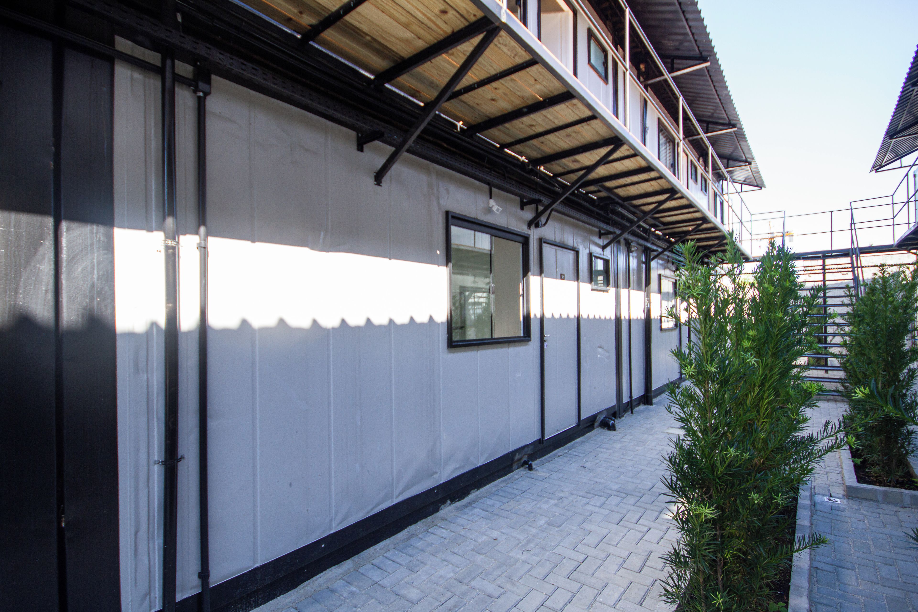 A building with a flat facade, large windows, and a covered walkway.