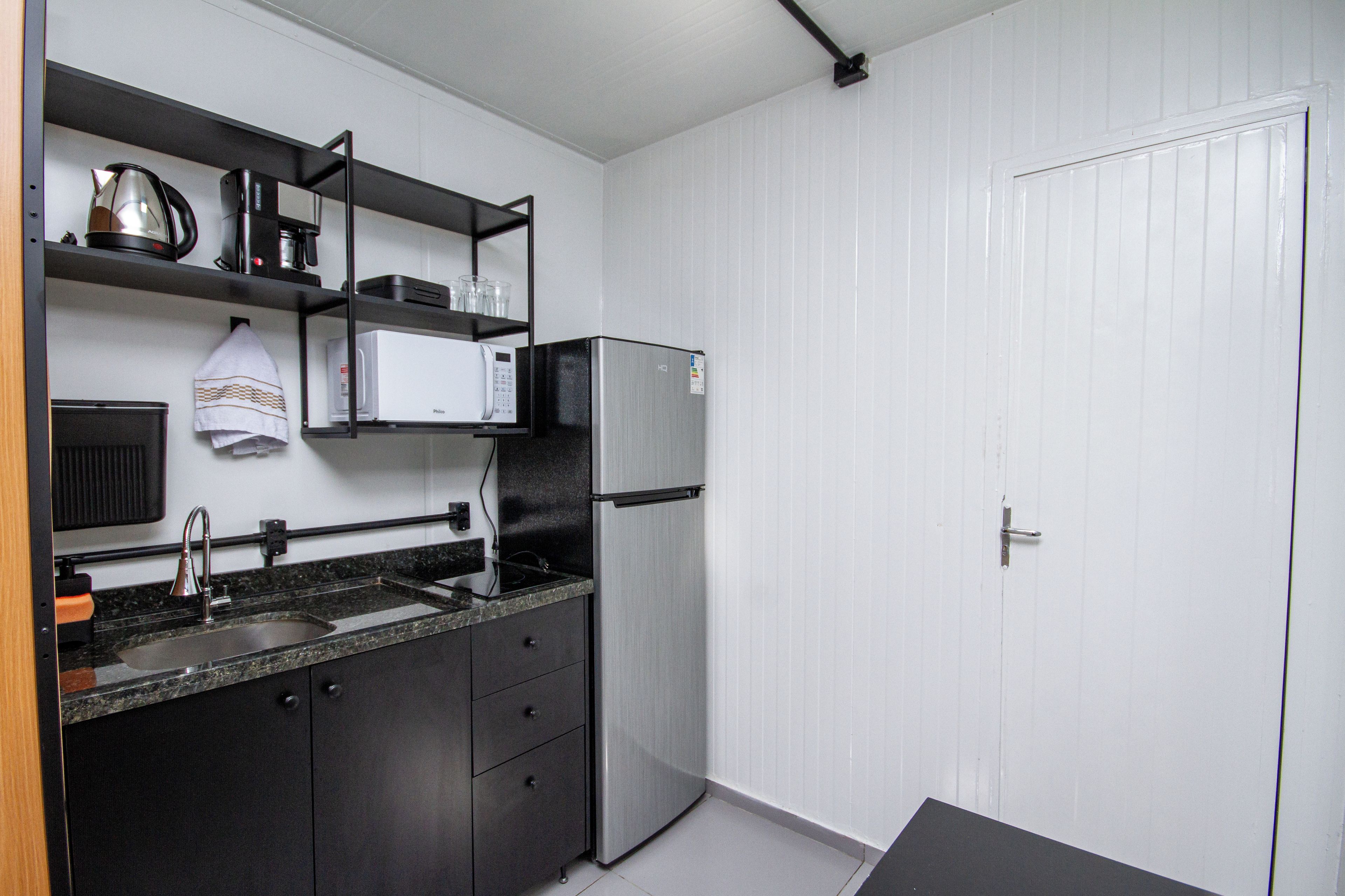 Una cocina compacta con fregadero, estufa, microondas y refrigerador.