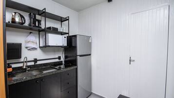 Una cocina compacta con fregadero, estufa, microondas y refrigerador.