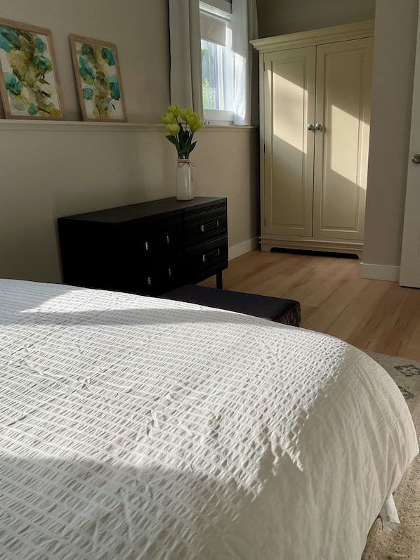 A bedroom with a bed, a dresser, a cabinet, and a window with curtains.