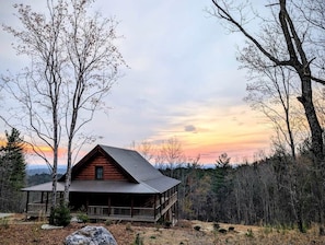 Eine Holzhütte mit Veranda und Blick auf den umliegenden Wald.