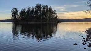 A calm lake with a small island of trees surrounded by calm water. - Shortoff Mountain Retreat | 3 Suites | Sleeps 12 (Burke County)
