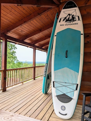A covered wooden deck with a surfboard leaning against the wall.