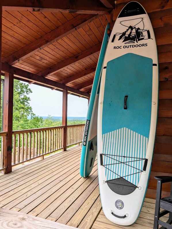 A covered wooden deck with a surfboard leaning against the wall.