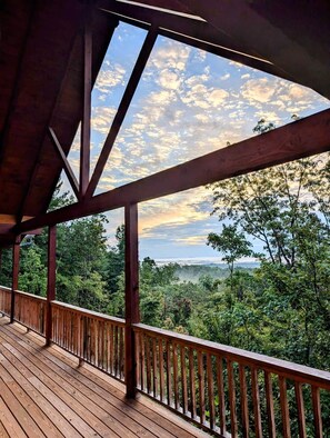 A wooden deck with a view of a forested landscape.
