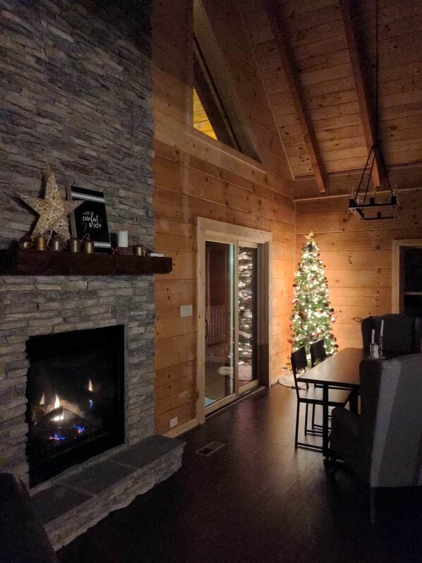 A cozy interior with a fireplace, a wooden ceiling, and a decorated Christmas tree.