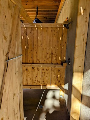 A wooden interior with a sloped ceiling, a hanging light fixture, and a visible door handle.