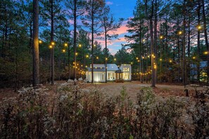 A cabin in a forest with string lights. - Large Deck! Hot tub! HorseShoe Set! Outdoor Dining (Broken Bow)