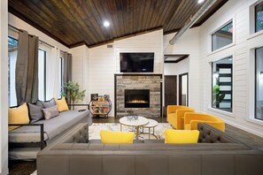 A modern living room with a fireplace, a sofa, and a television. - Large Deck! Hot tub! HorseShoe Set! Outdoor Dining (Broken Bow)