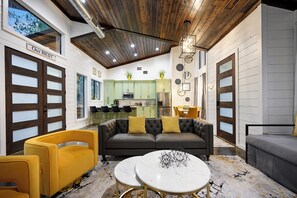 A modern interior with a dark leather sofa, yellow armchairs, and a marble coffee table. - Large Deck! Hot tub! HorseShoe Set! Outdoor Dining (Broken Bow)