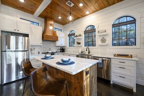 A modern kitchen with a central island, stainless steel appliances, and wooden accents. - Romantic Cottage, Pond, Fishing, Swings (Broken Bow)
