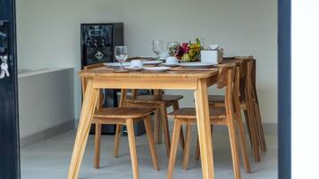 Una mesa con sillas, platos, vasos y un frutero.