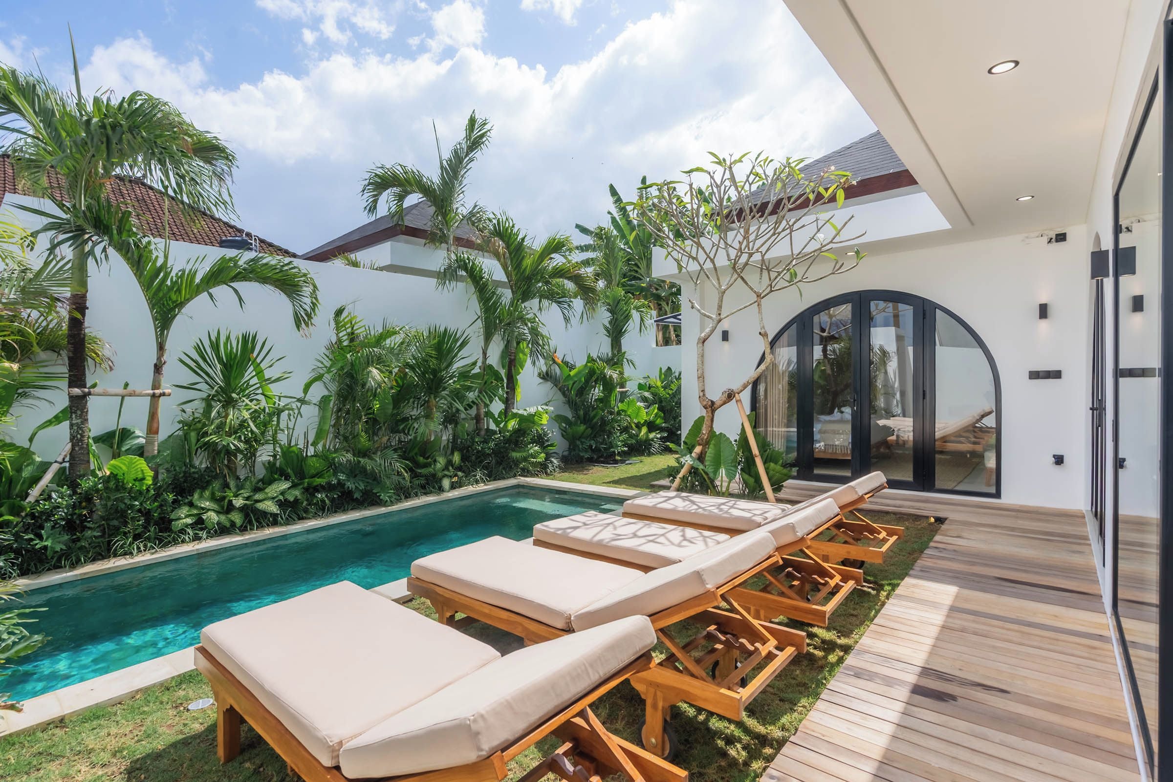 Un espace piscine extérieur moderne, doté de chaises longues et d’une terrasse en bois.