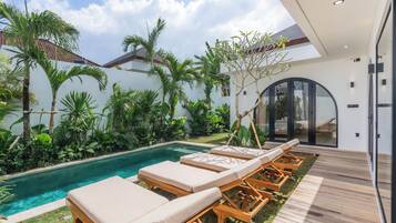 Un espace piscine extérieur moderne, doté de chaises longues et d’une terrasse en bois.