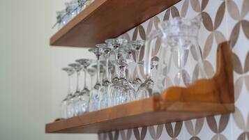 En hylla i trä med flera vinglas av klart glas.