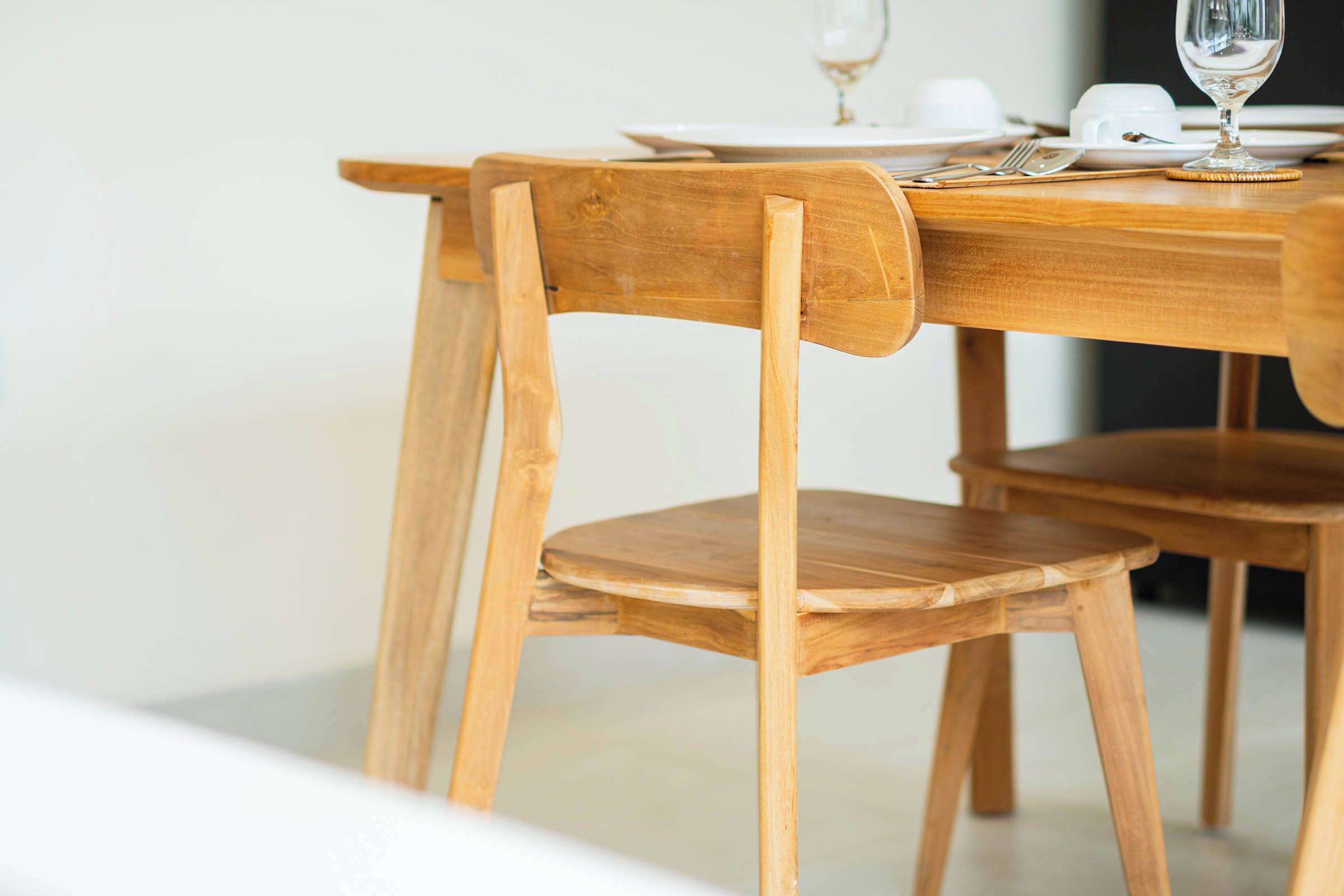 Ein Holztisch mit Stühlen, einem Glas und weißen Tellern.