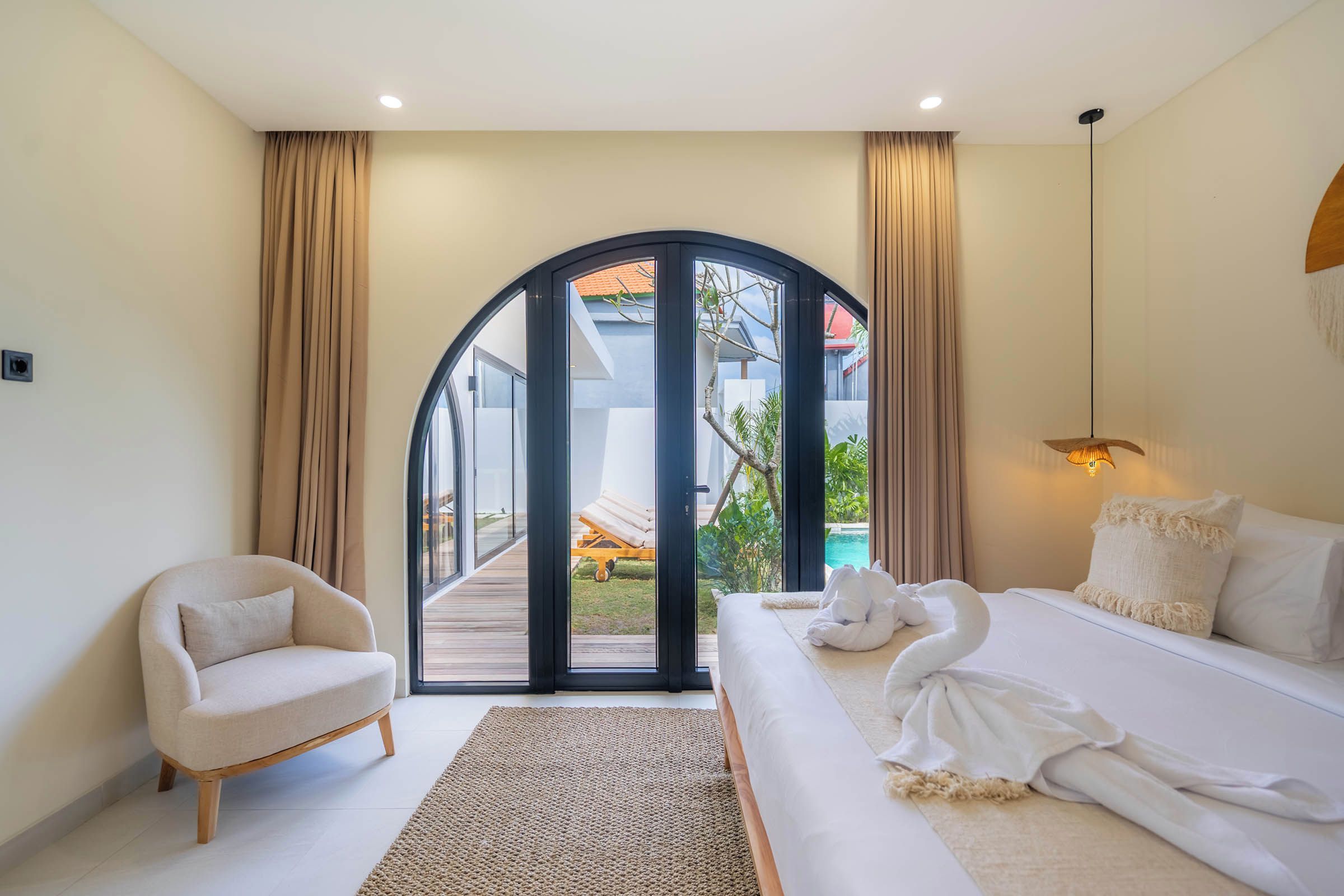 Une chambre avec un lit, une chaise, un tapis et une vue sur une piscine, visible à travers une porte vitrée.
