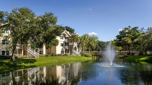 Ein Hotel mit Springbrunnen, umgeben von Bäumen und einem Teich.