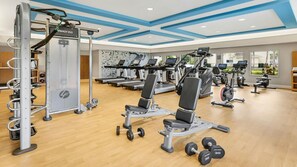 Ein modernes Fitnessstudio mit verschiedenen Trainingsgeräten, darunter Laufbänder, Crosstrainer und Kraftgeräte.