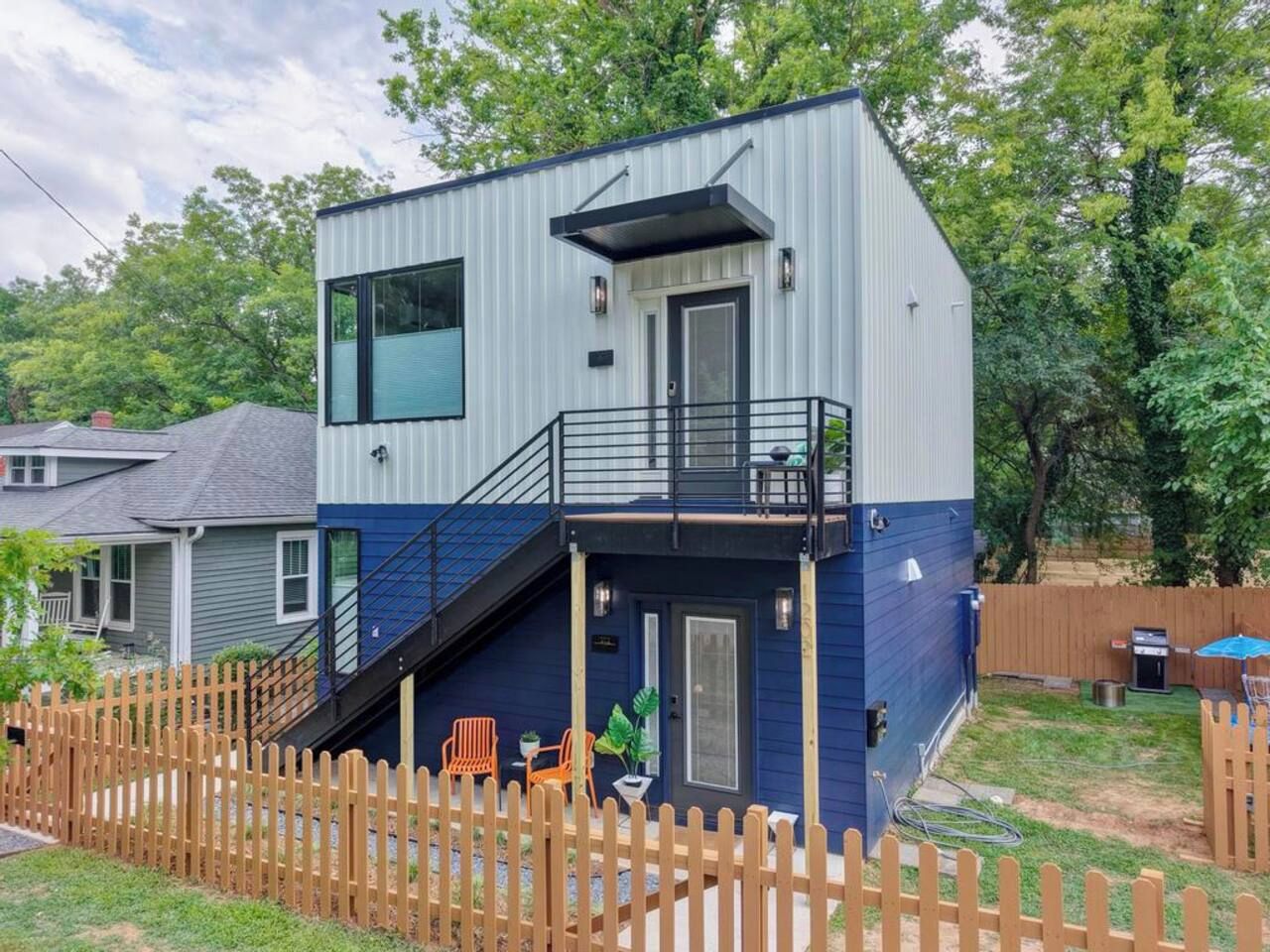 A two-story house with a balcony, a wooden fence, and outdoor seating.
