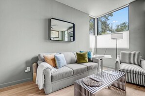 A modern living room with a grey sofa, striped armchair, and a coffee table with a woven placemat.