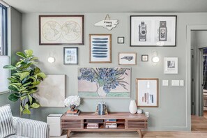 A living room with a wooden console table, framed artwork, and a potted plant.