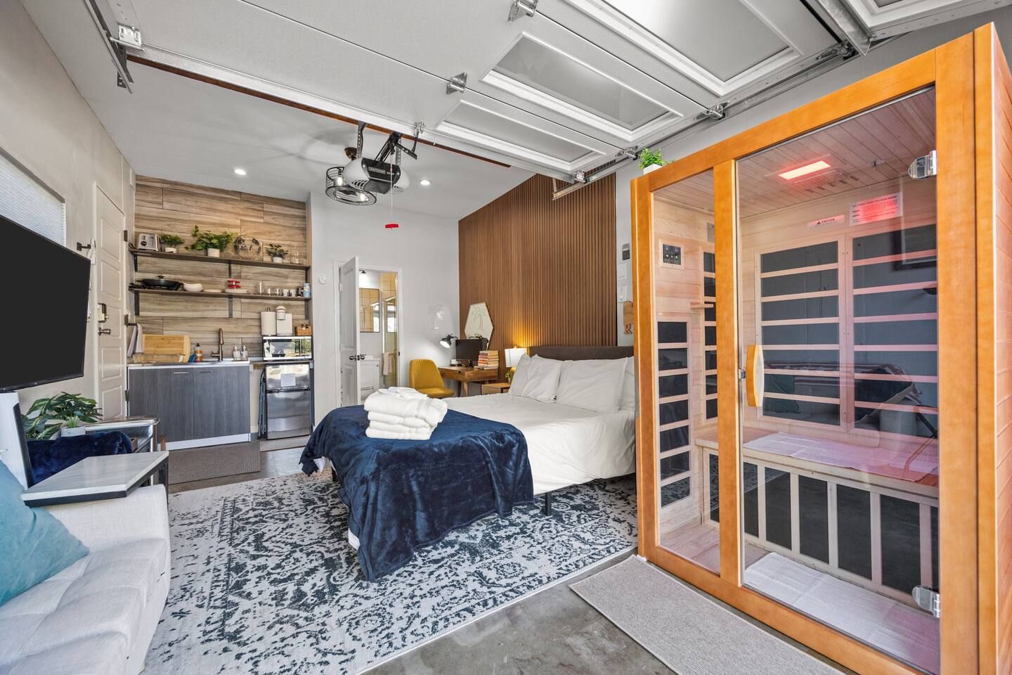 Een moderne hotelkamer met een bed, een bureau, een televisie en een schuifdeur naar een badkamer.