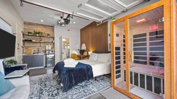 Een moderne hotelkamer met een bed, een bureau, een televisie en een schuifdeur naar een badkamer.