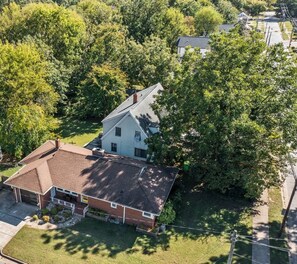 A two-story house with a sloped roof, surrounded by trees and a well-maintained lawn.
