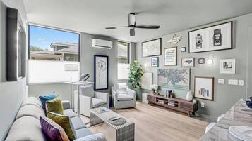 Een moderne woonkamer met een bank, gestreepte stoelen, een salontafel en een eethoek met een marmeren tafel.