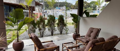 Un balcón con mobiliario de mimbre y plantas en macetas, con vistas a una zona residencial.
