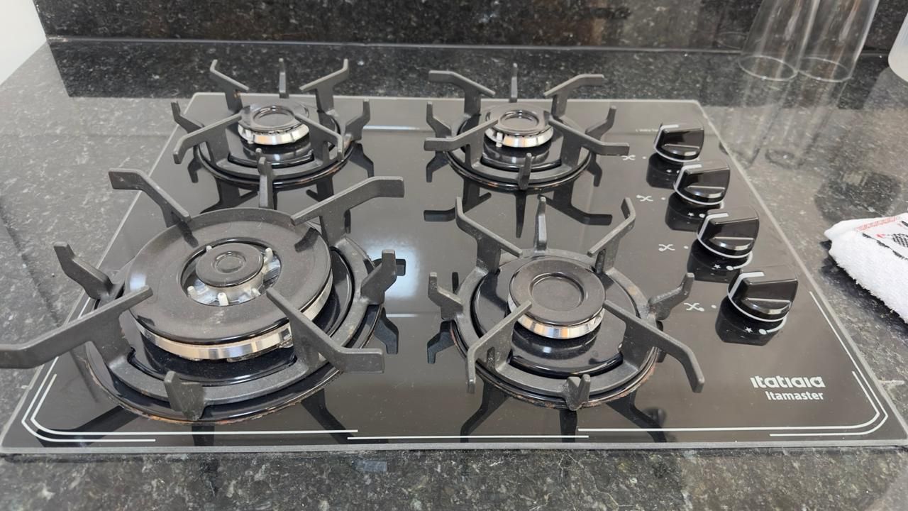 Una cucina con un piano cottura a gas a quattro fuochi e un piano in vetro.