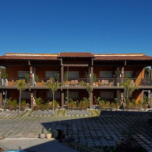 A hotel with a two-story structure, outdoor seating, and a paved courtyard. - MANDACARU POUSADA (Aracruz)