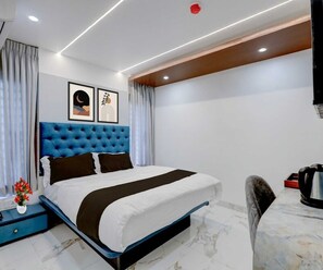 A modern hotel room with a large bed, a nightstand, a coffee maker, and artwork on the wall. - Deluxe Room Periyar Stay (Peermade)
