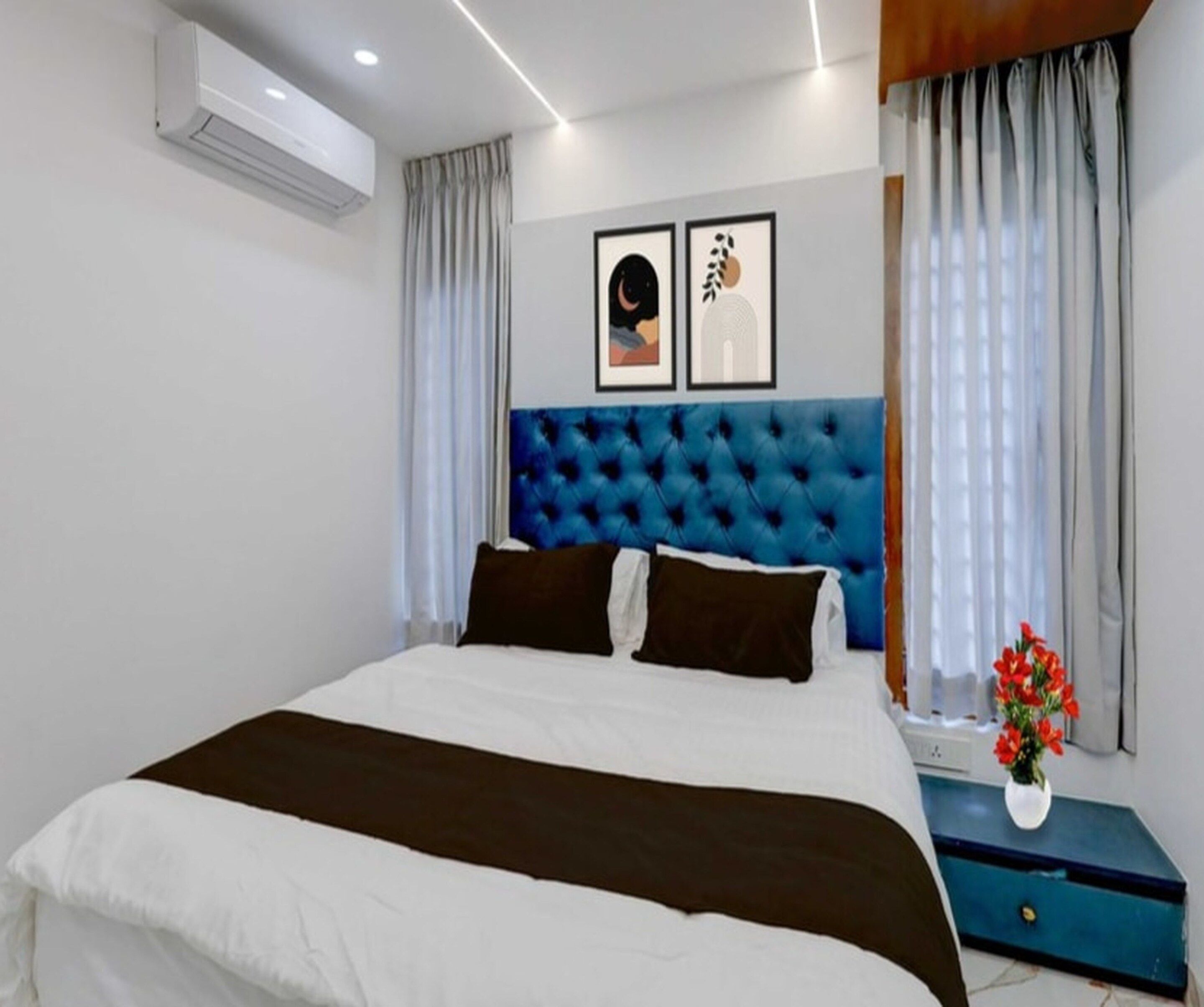Una camera d'albergo moderna con un letto grande, una testiera blu e un condizionatore d'aria a parete.