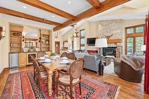 A spacious living area with a fireplace, wooden beams, and a dining table set for six. - Beaver Creek True Ski-In/Ski-Out | Private Hot Tub (Beaver Creek)