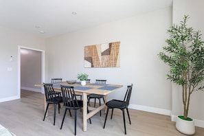 Uma área de refeições com mesa, cadeiras e um vaso de planta.