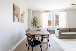 Uma área de refeições com mesa de madeira, cadeiras pretas e uma planta.