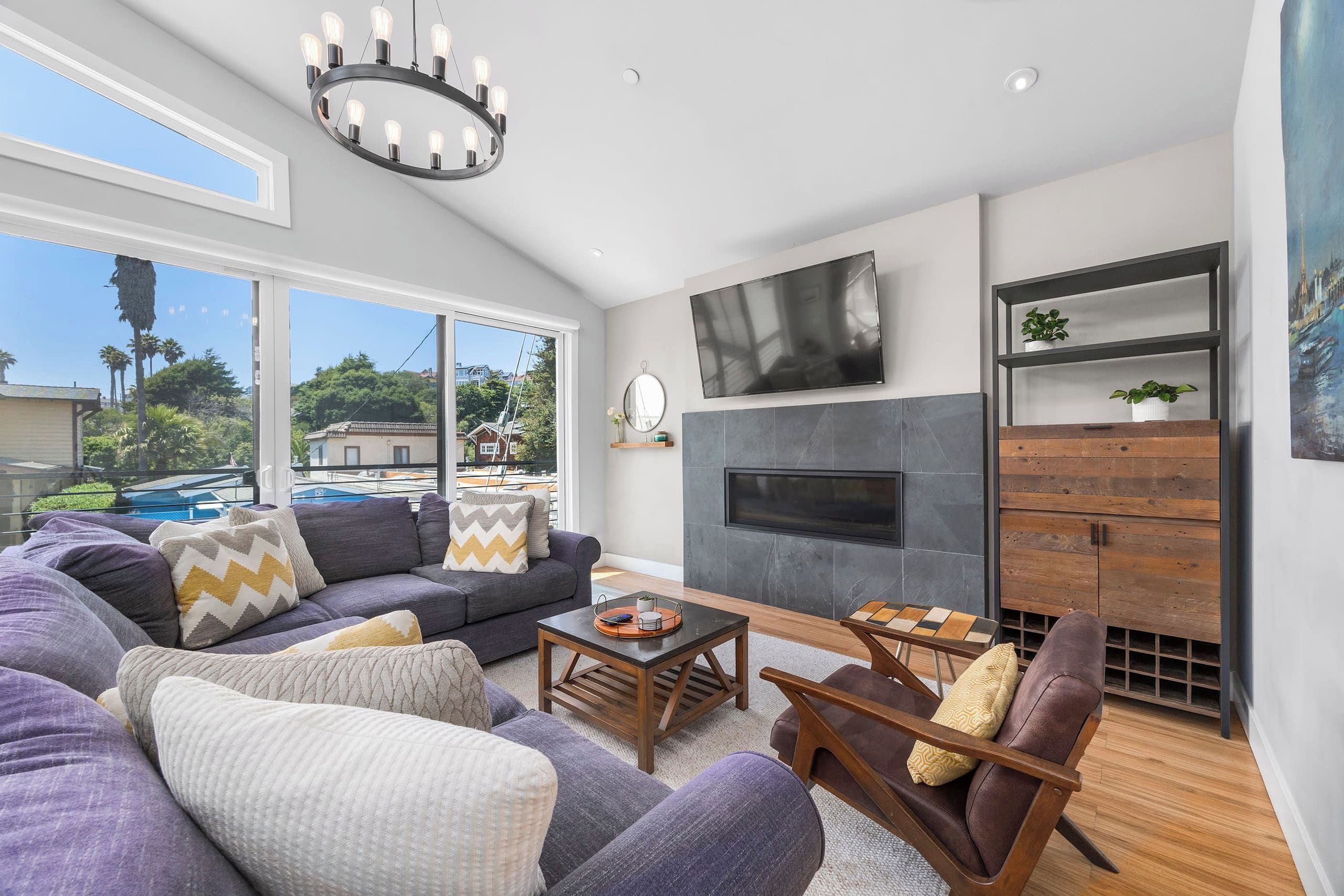 A modern living room with a sectional sofa, a coffee table, a fireplace, and a TV mounted on the wall.