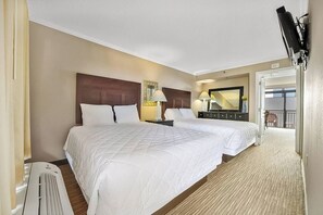 A hotel room with two beds, a large mirror, a TV mounted on the wall, and a view of the balcony. - Cozy 1-bedroom condo in charming Myrtle Beach with AC and gym (Myrtle Beach)