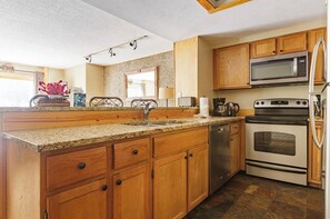 A kitchen with wooden cabinets, a granite countertop, stainless steel appliances including a microwave and oven, and a built-in dishwasher. - Beautiful 3Bd 4Bt townhome in Breckenridge perfect for mountain sports getaways (Breckenridge)
