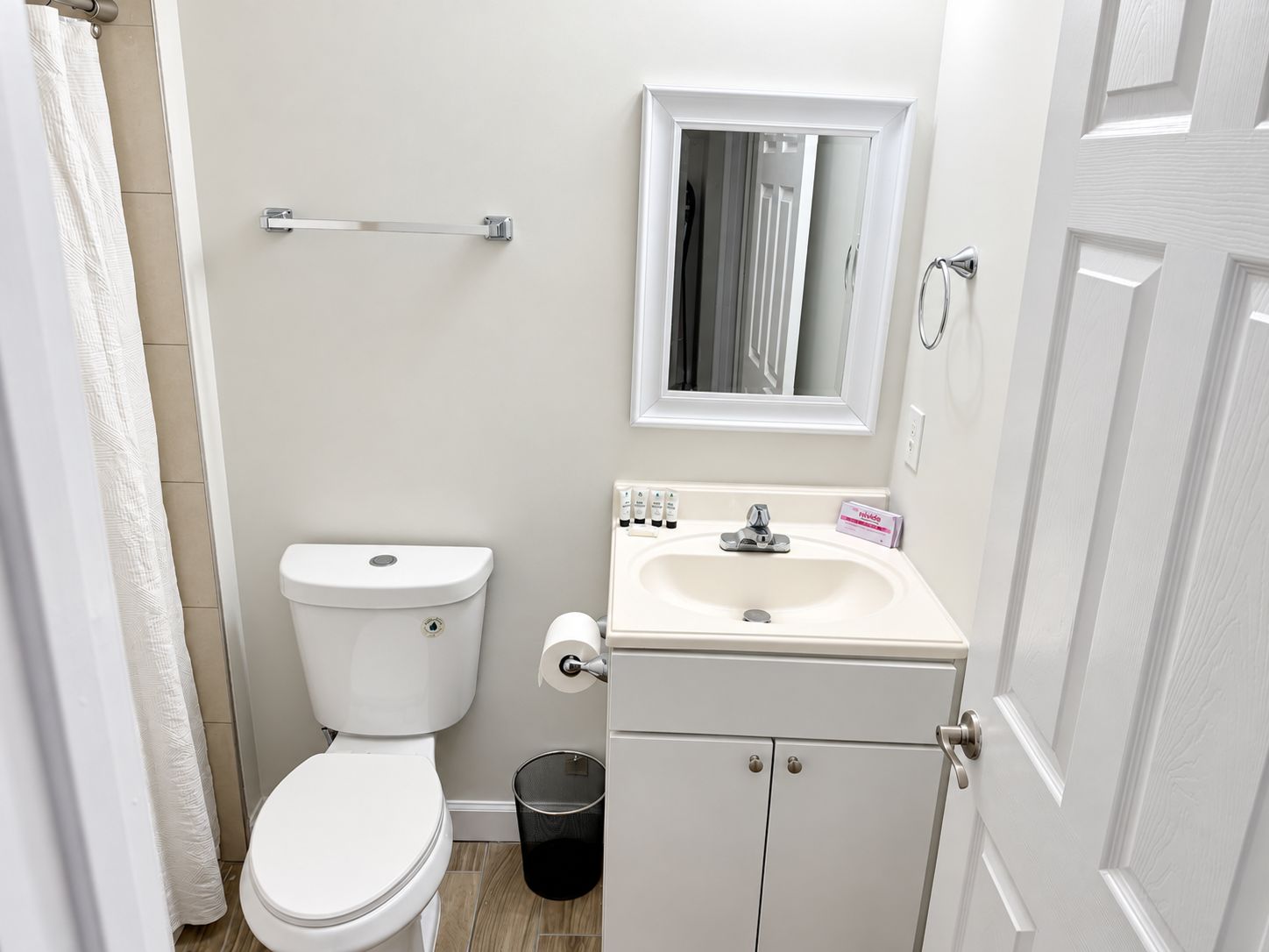 Une petite salle de bain avec des toilettes, un lavabo et un miroir au-dessus du lavabo.