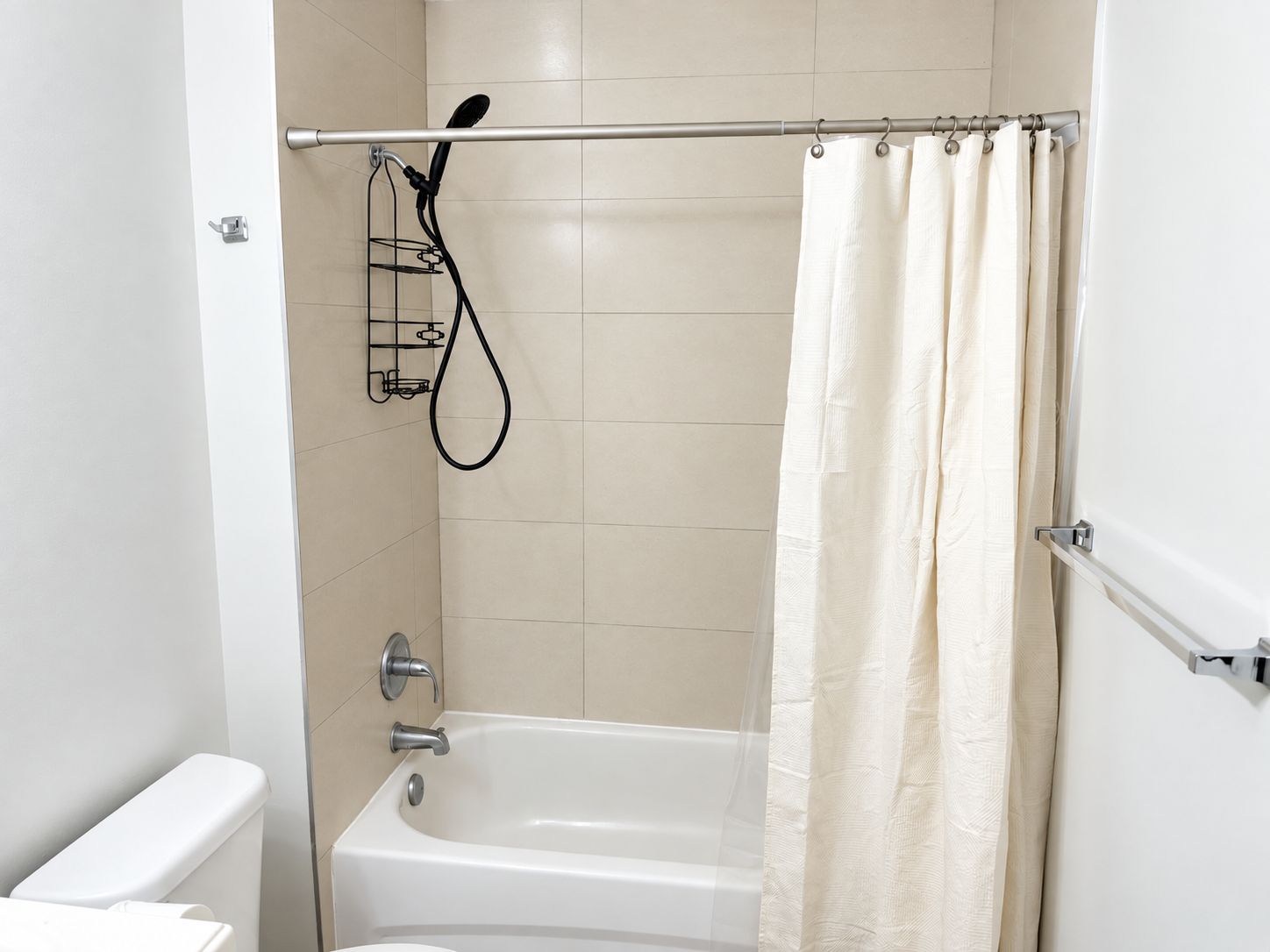 A bathroom with a bathtub, a shower head, and a curtain.